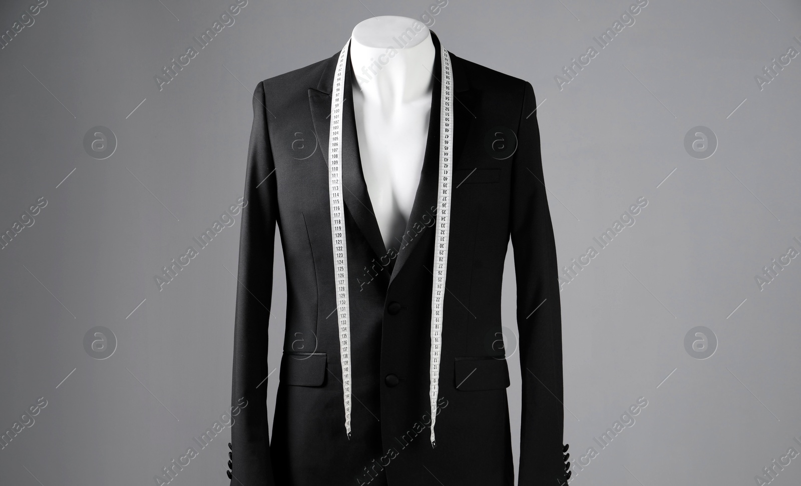 Photo of Male mannequin with black jacket and measuring tape on grey background