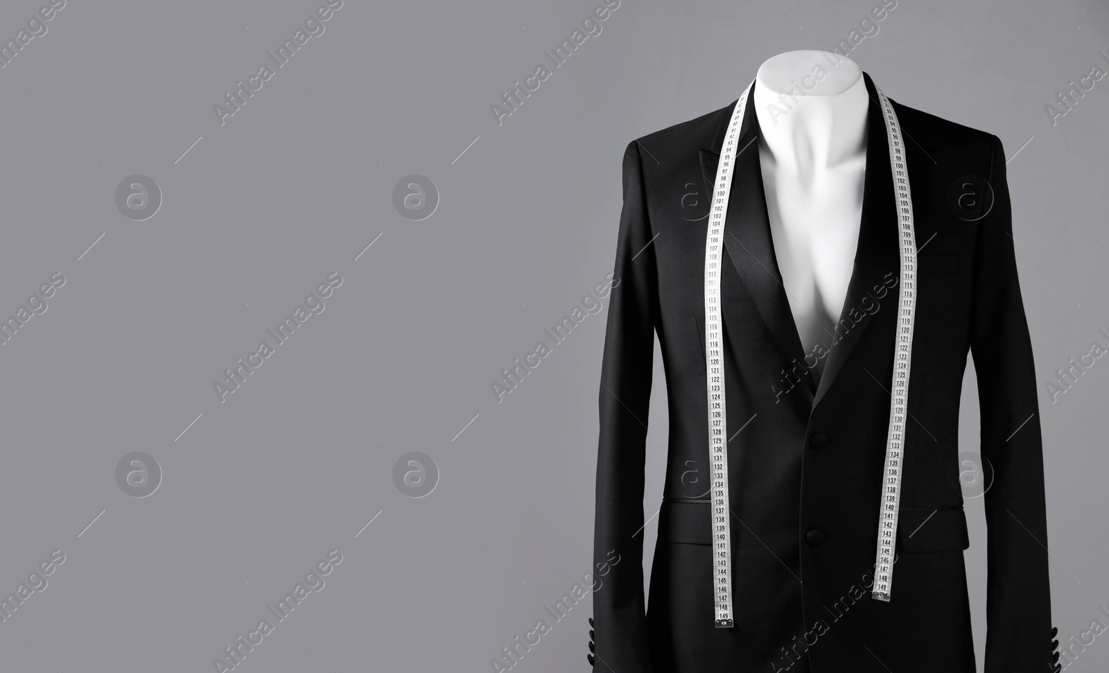 Photo of Male mannequin with black jacket and measuring tape on grey background, space for text