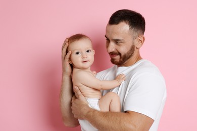 Photo of Father with his cute baby on pink background