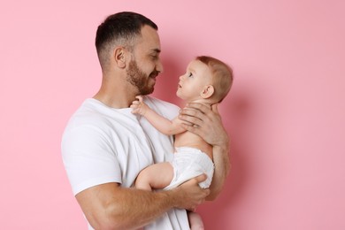 Father with his cute baby on pink background