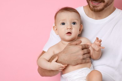 Photo of Father with his cute baby on pink background, space for text