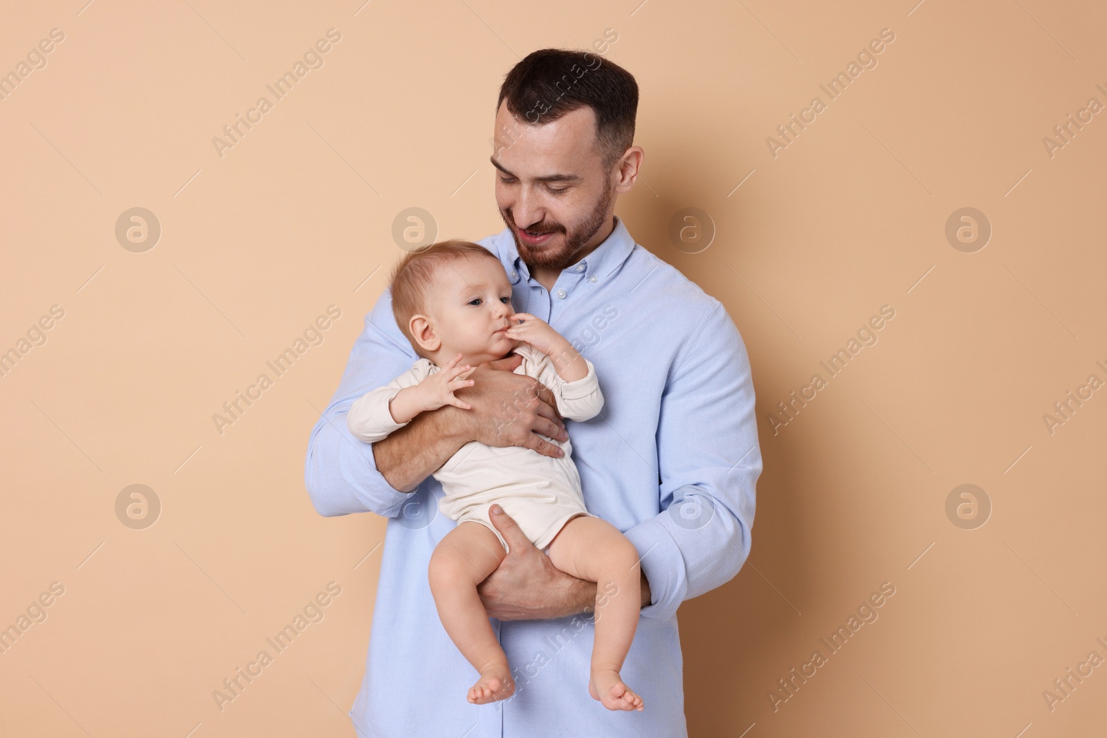 Photo of Father with his cute baby on beige background