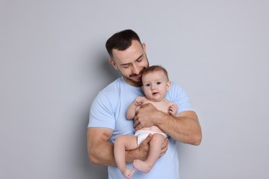 Photo of Father with his cute baby on grey background