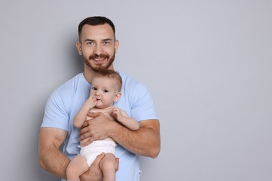 Photo of Father with his cute baby on grey background, space for text