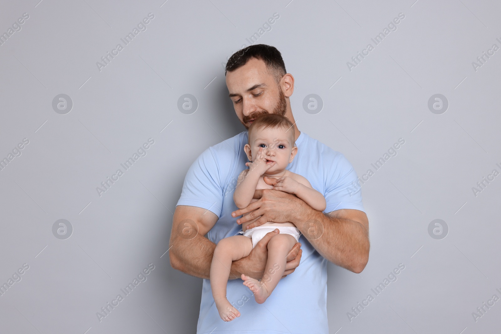 Photo of Father with his cute baby on grey background