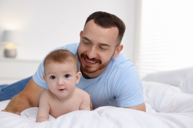 Photo of Father with his cute baby on bed at home