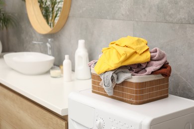 Photo of Basket with laundry on washing machine in bathroom