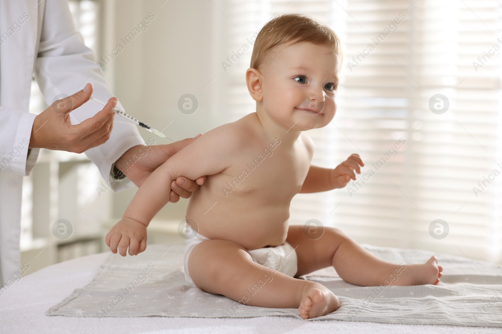 Photo of Pediatrician giving injection to cute baby in clinic, closeup