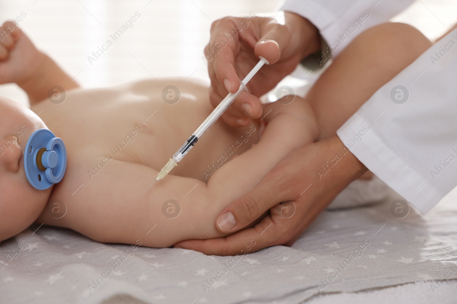 Photo of Pediatrician giving injection to baby in clinic, closeup