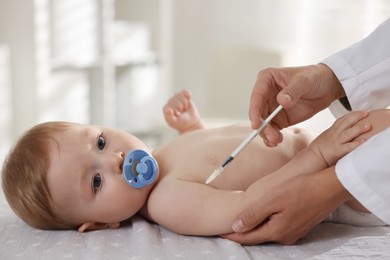 Photo of Pediatrician giving injection to cute baby in clinic, closeup