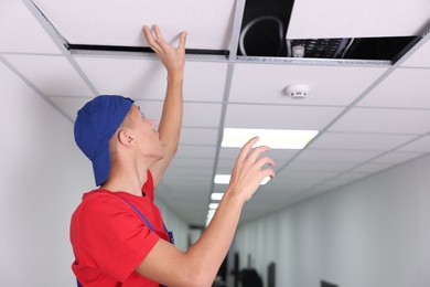 Photo of Suspended ceiling installation. Builder working with PVC tile indoors