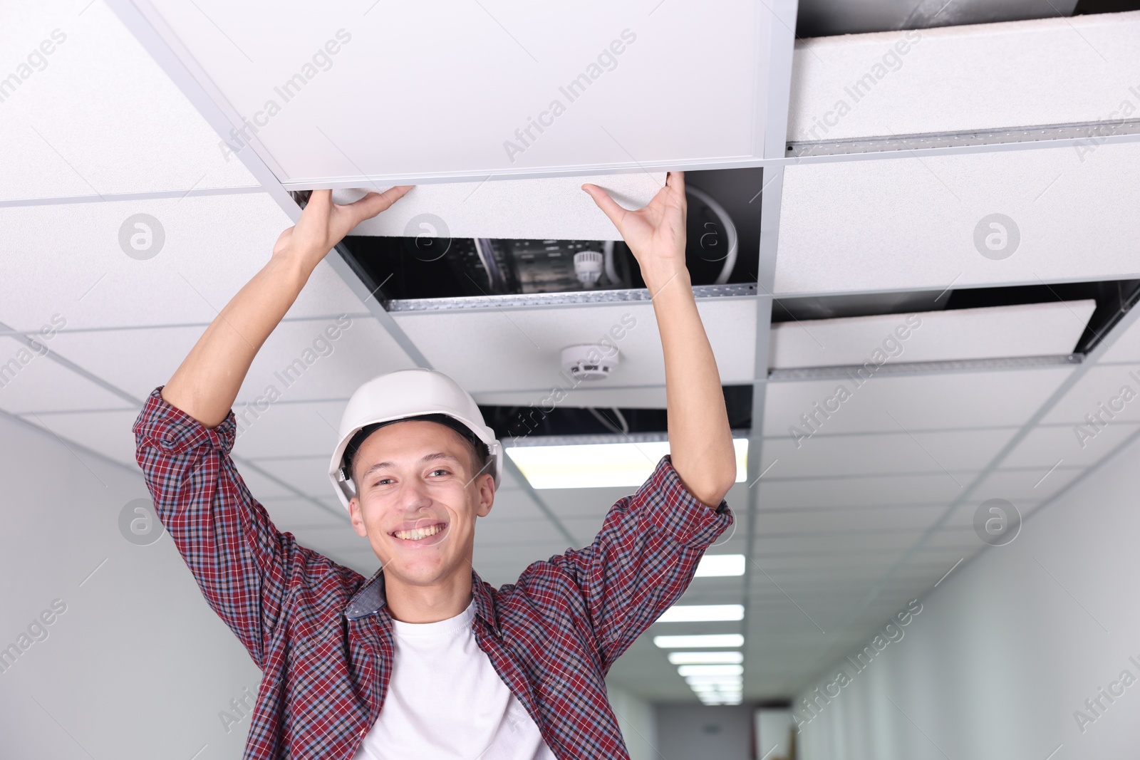 Photo of Suspended ceiling installation. Builder working with PVC tile indoors