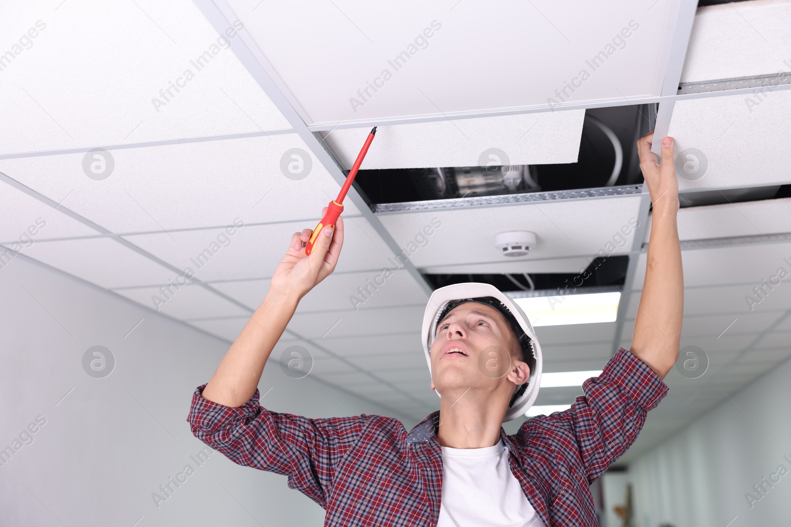 Photo of Suspended ceiling installation. Builder working with PVC tile indoors