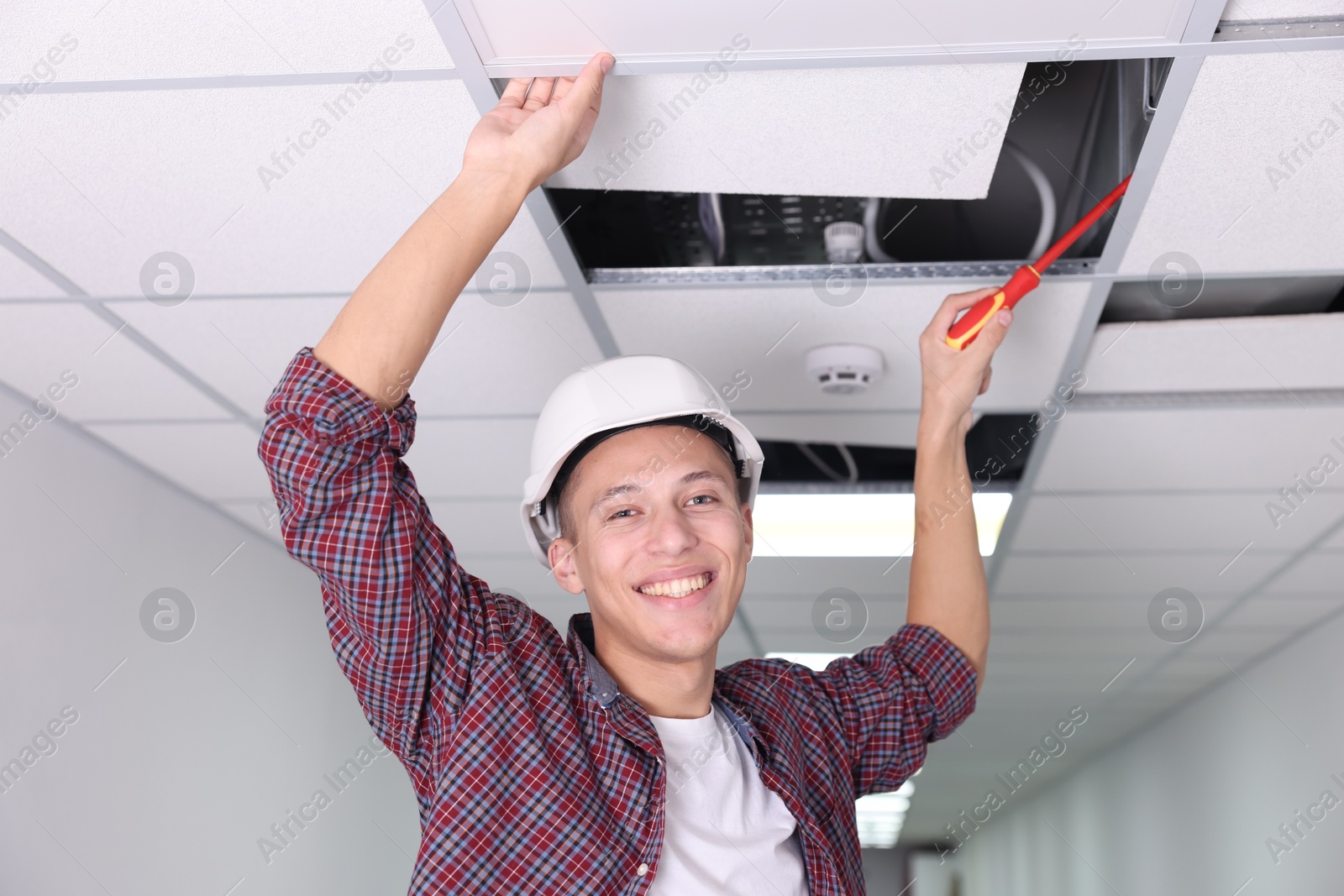 Photo of Suspended ceiling installation. Builder working with PVC tile indoors