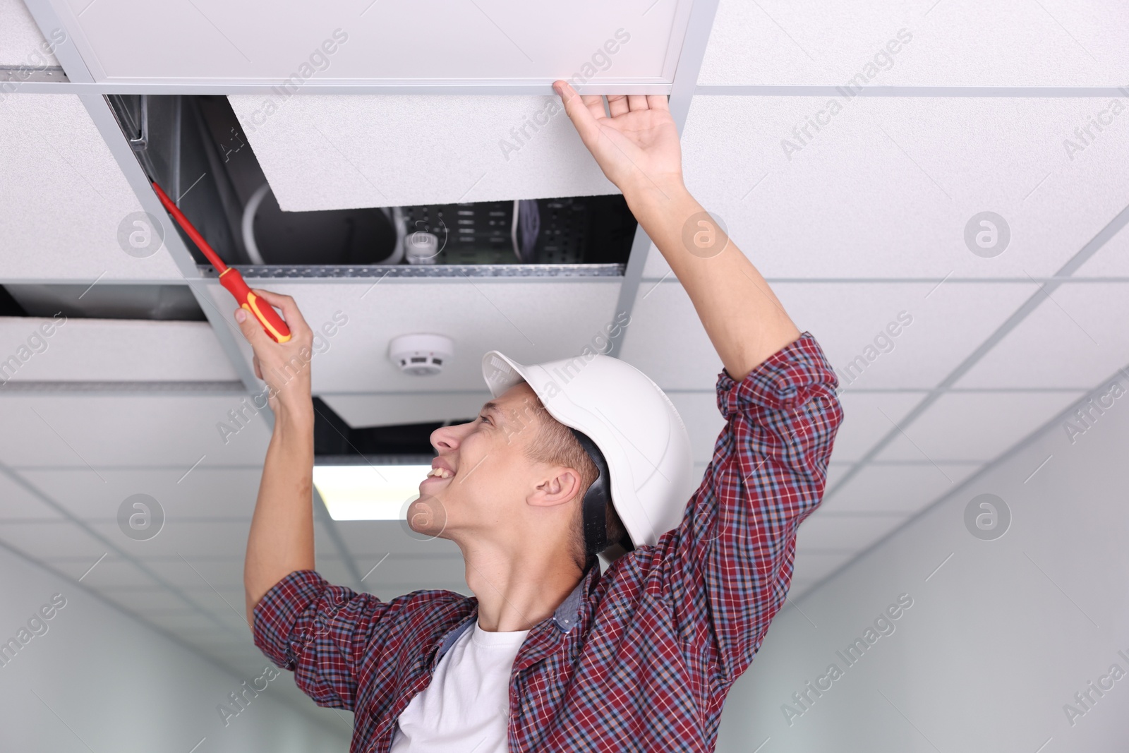 Photo of Suspended ceiling installation. Builder working with PVC tile indoors