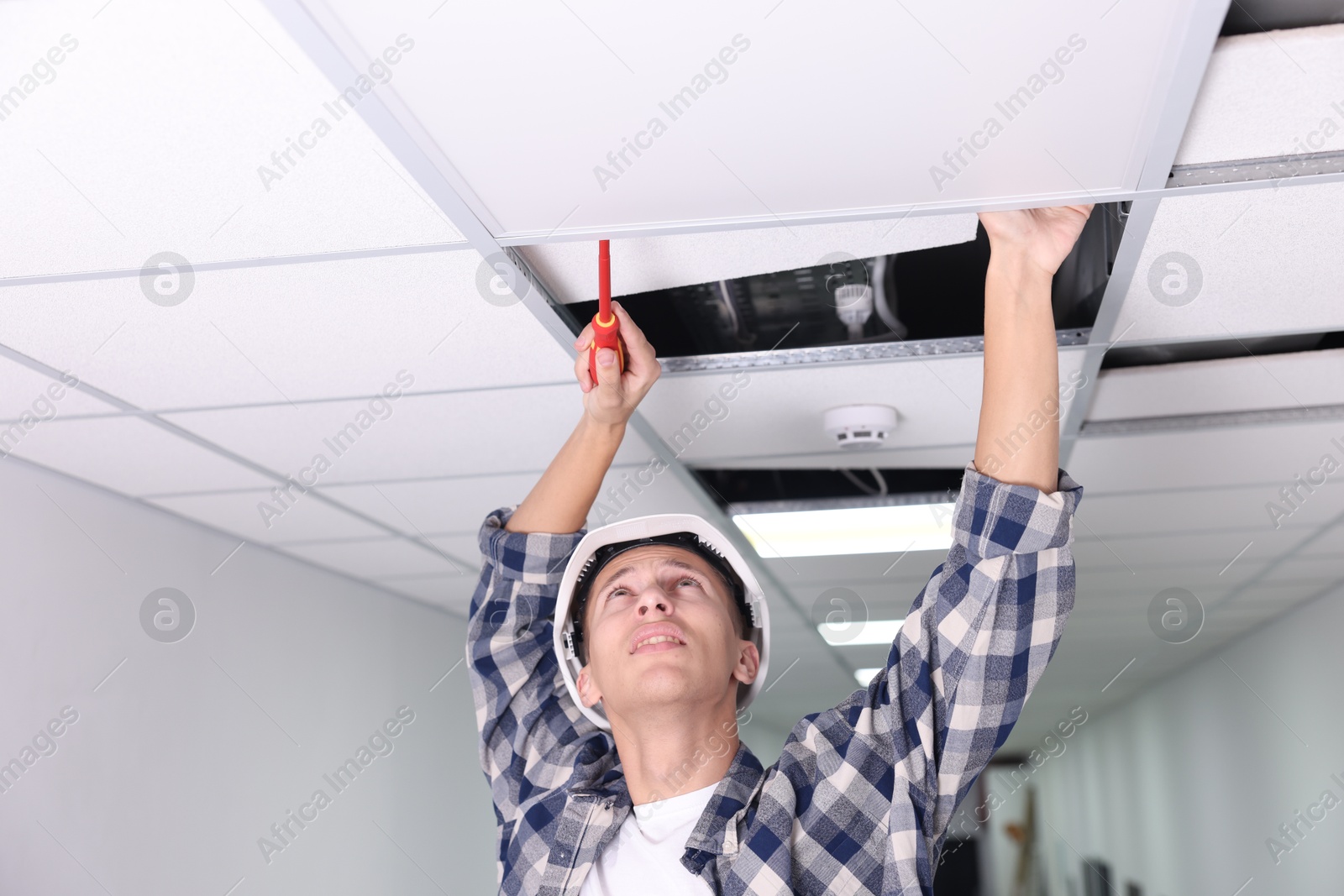 Photo of Suspended ceiling installation. Builder working with PVC tile indoors