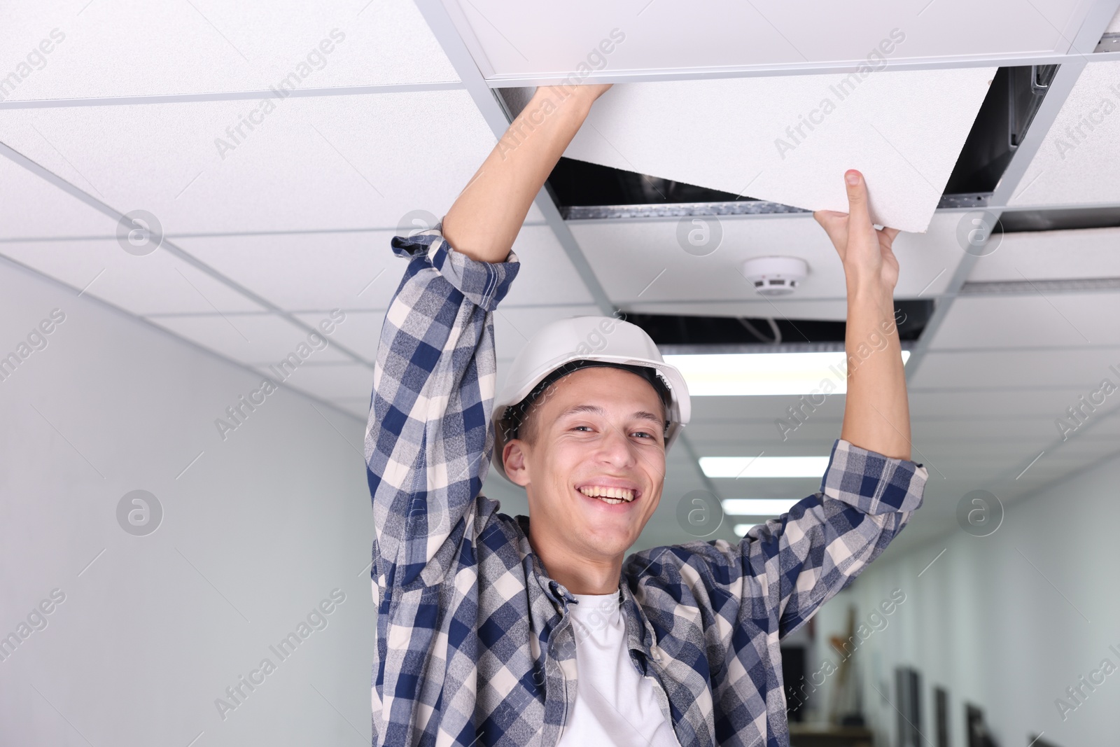 Photo of Suspended ceiling installation. Builder working with PVC tile indoors