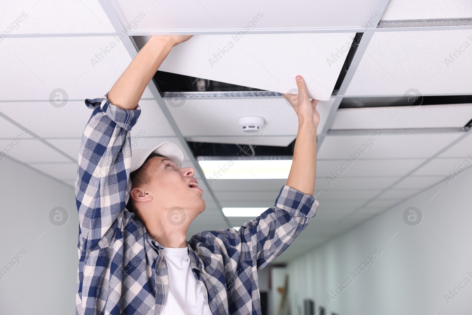 Photo of Suspended ceiling installation. Builder working with PVC tile indoors