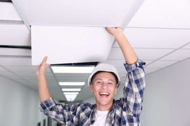 Photo of Suspended ceiling installation. Builder working with PVC tile indoors