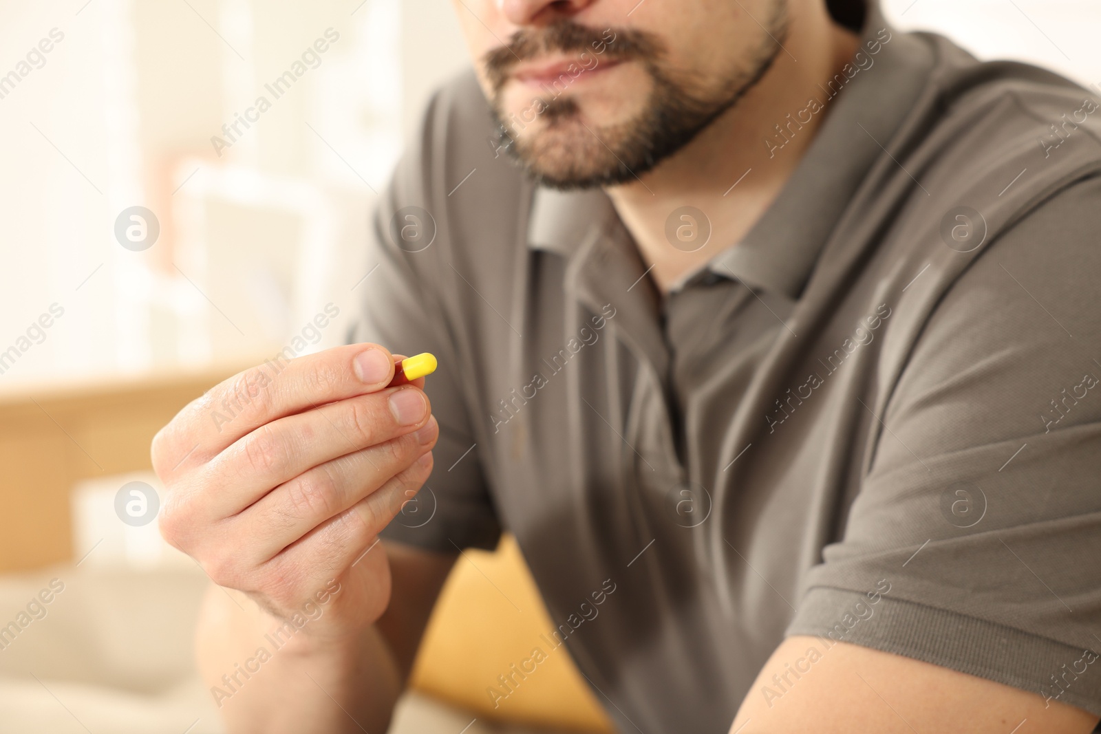 Photo of Man with pill at home, closeup on hand