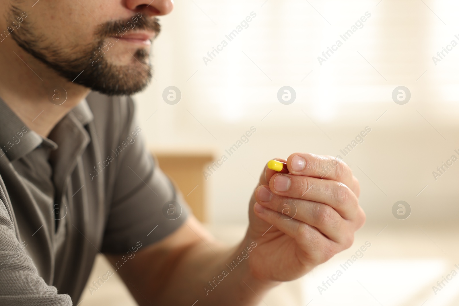 Photo of Man with pill at home, closeup on hand