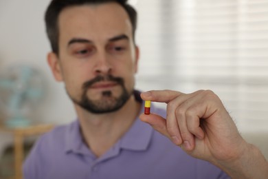 Photo of Man with pill at home, selective focus