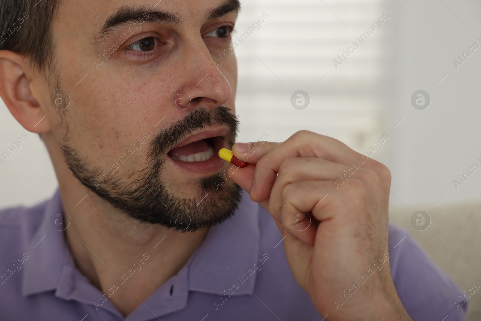 Photo of Man taking pill at home, closeup view