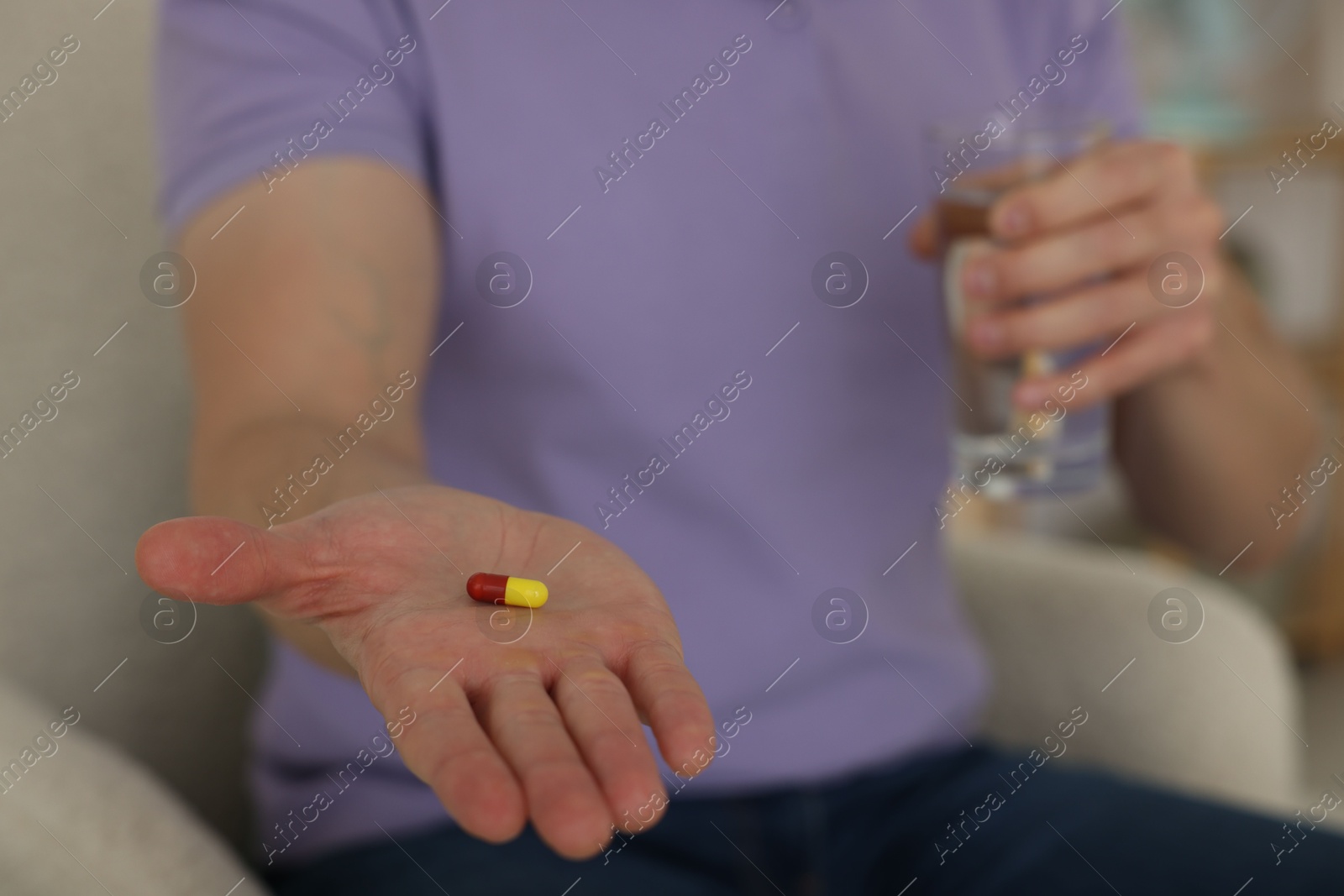 Photo of Man with pill and glass of water at home, closeup