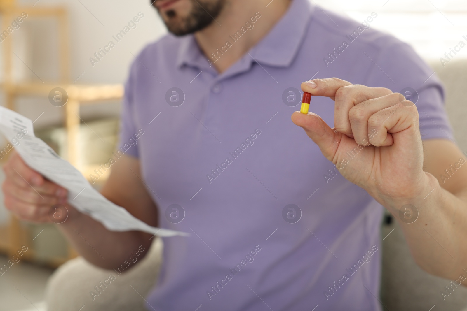 Photo of Man with pill reading instruction at home, selective focus