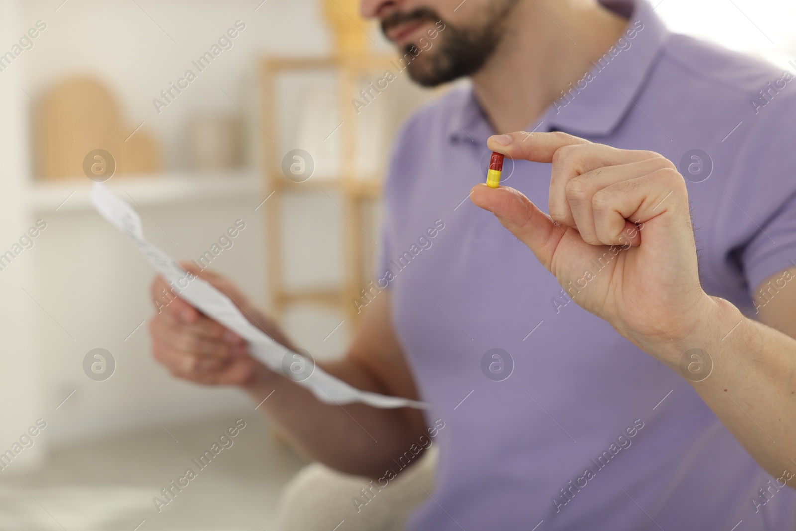 Photo of Man with pill reading instruction at home, selective focus