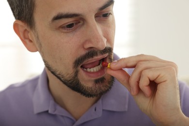 Photo of Man taking pill at home, closeup view