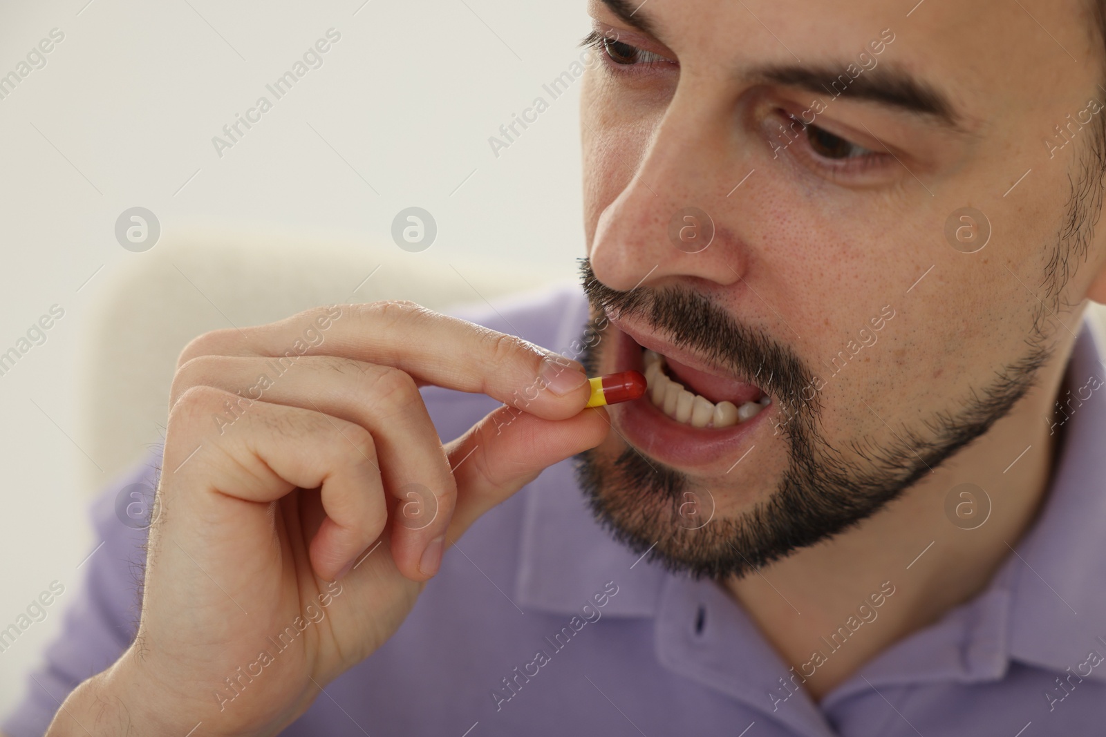 Photo of Man taking pill at home, closeup view