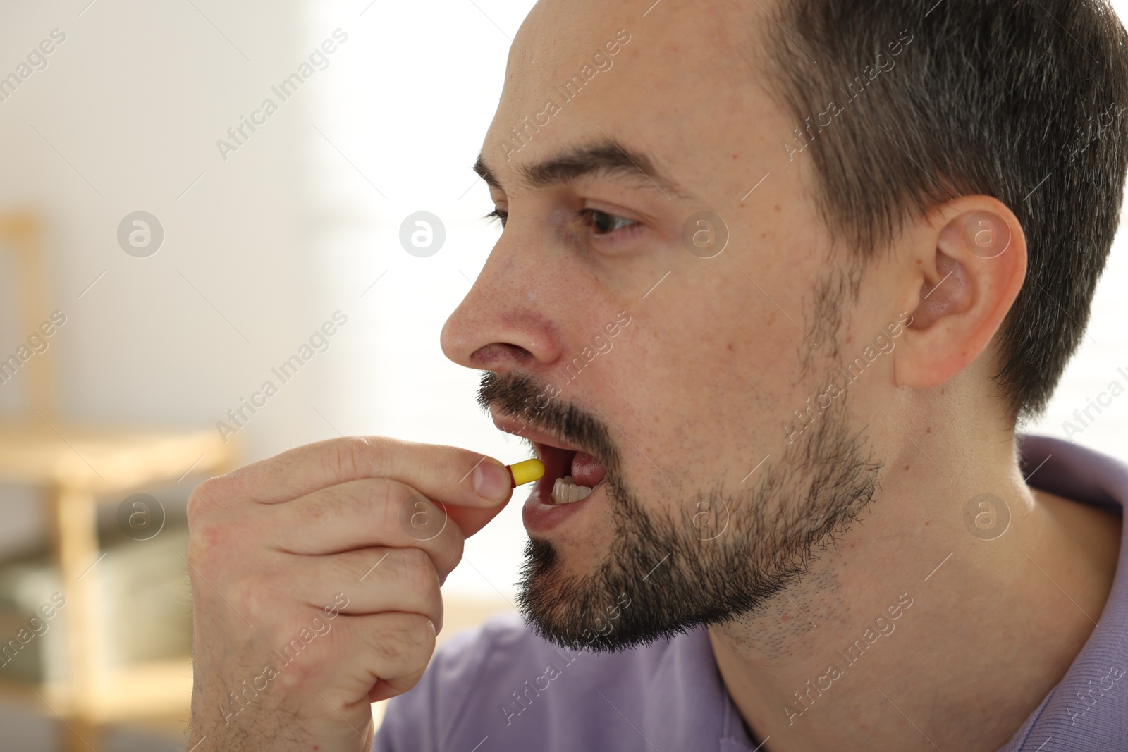 Photo of Man taking pill at home, closeup view