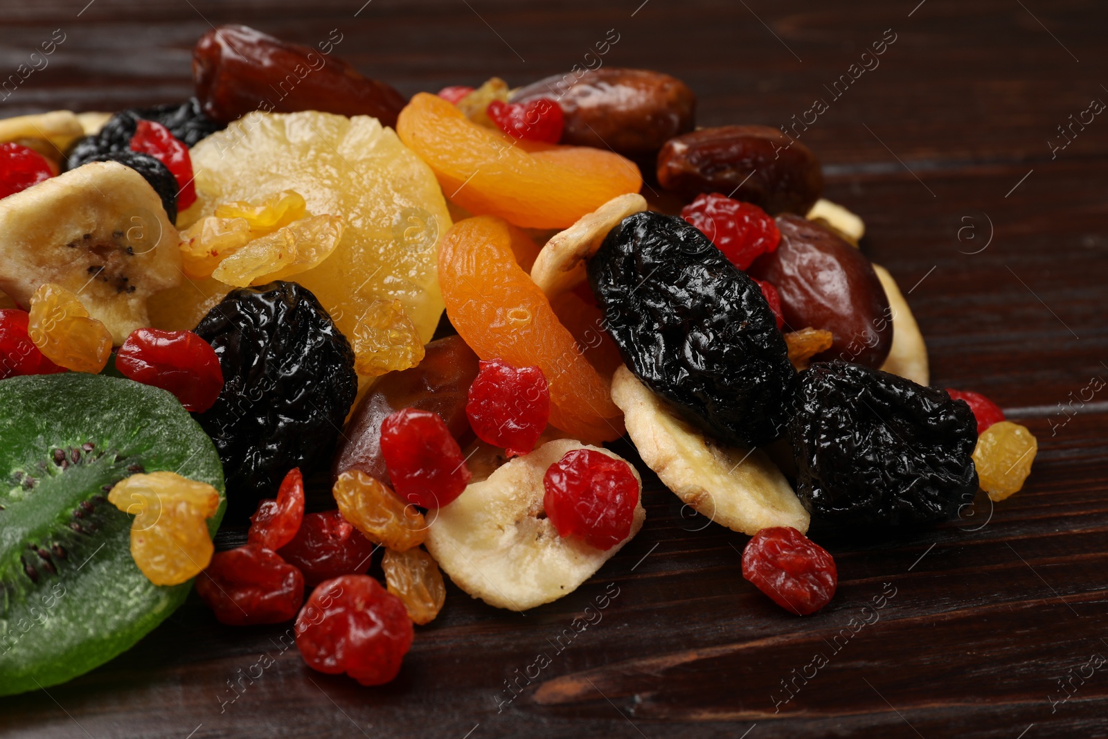 Photo of Mix of different dried fruits on wooden table, closeup