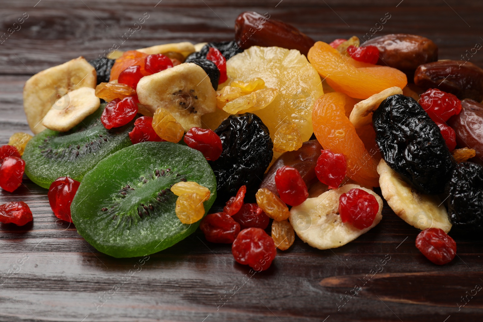 Photo of Mix of different dried fruits on wooden table, closeup