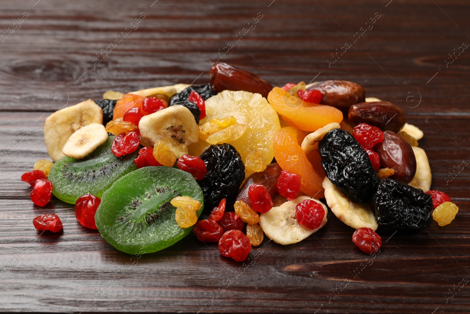 Photo of Mix of different dried fruits on wooden table, closeup