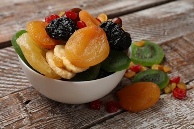 Photo of Mix of different dried fruits in bowl on wooden table, closeup