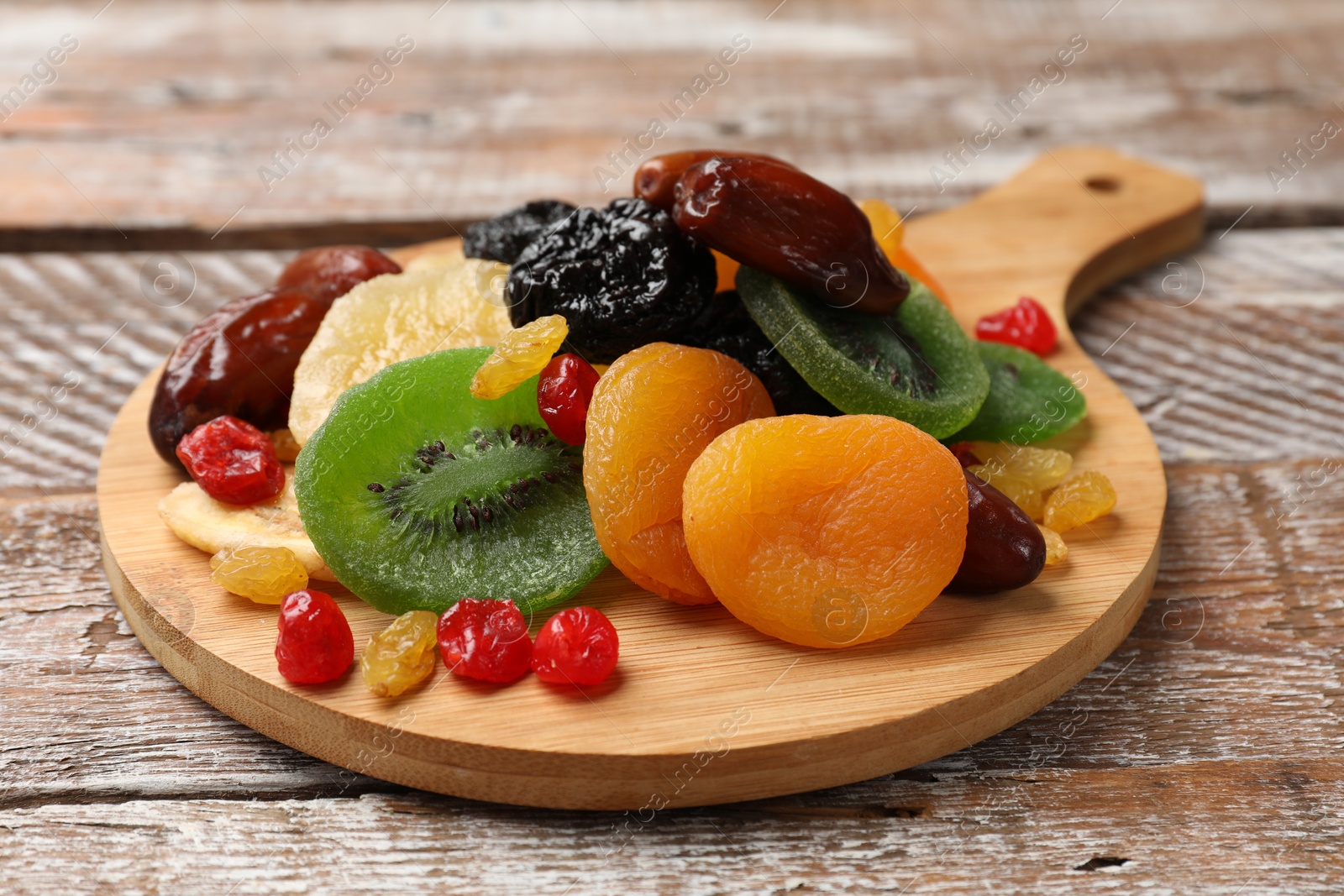 Photo of Mix of different dried fruits on wooden table, closeup