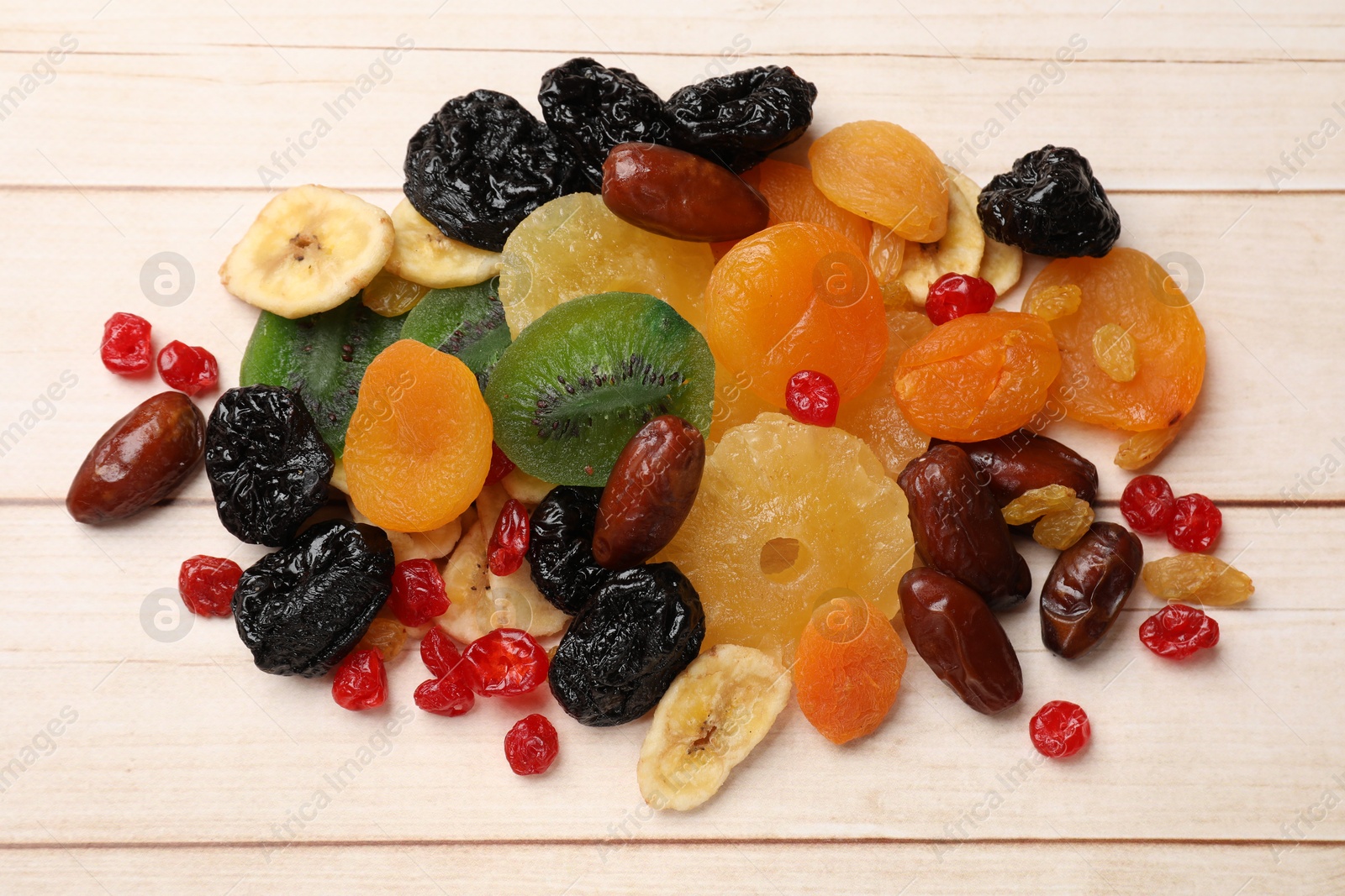 Photo of Mix of different dried fruits on wooden table, top view