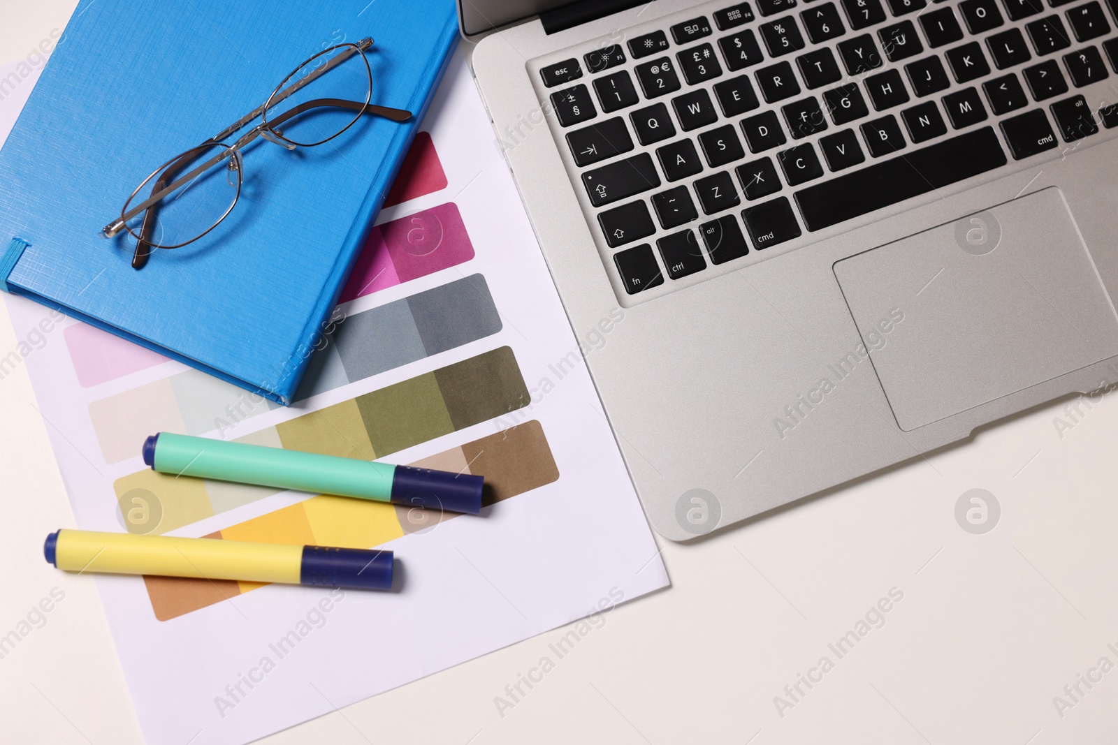 Photo of Designer's workplace with laptop and palette on white table, flat lay