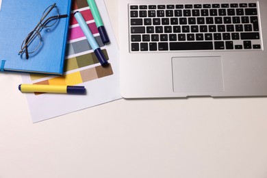 Photo of Designer's workplace with laptop and palette on white table, flat lay. Space for text