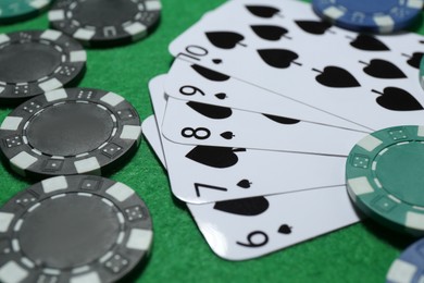 Photo of Playing cards and poker chips on green table, closeup