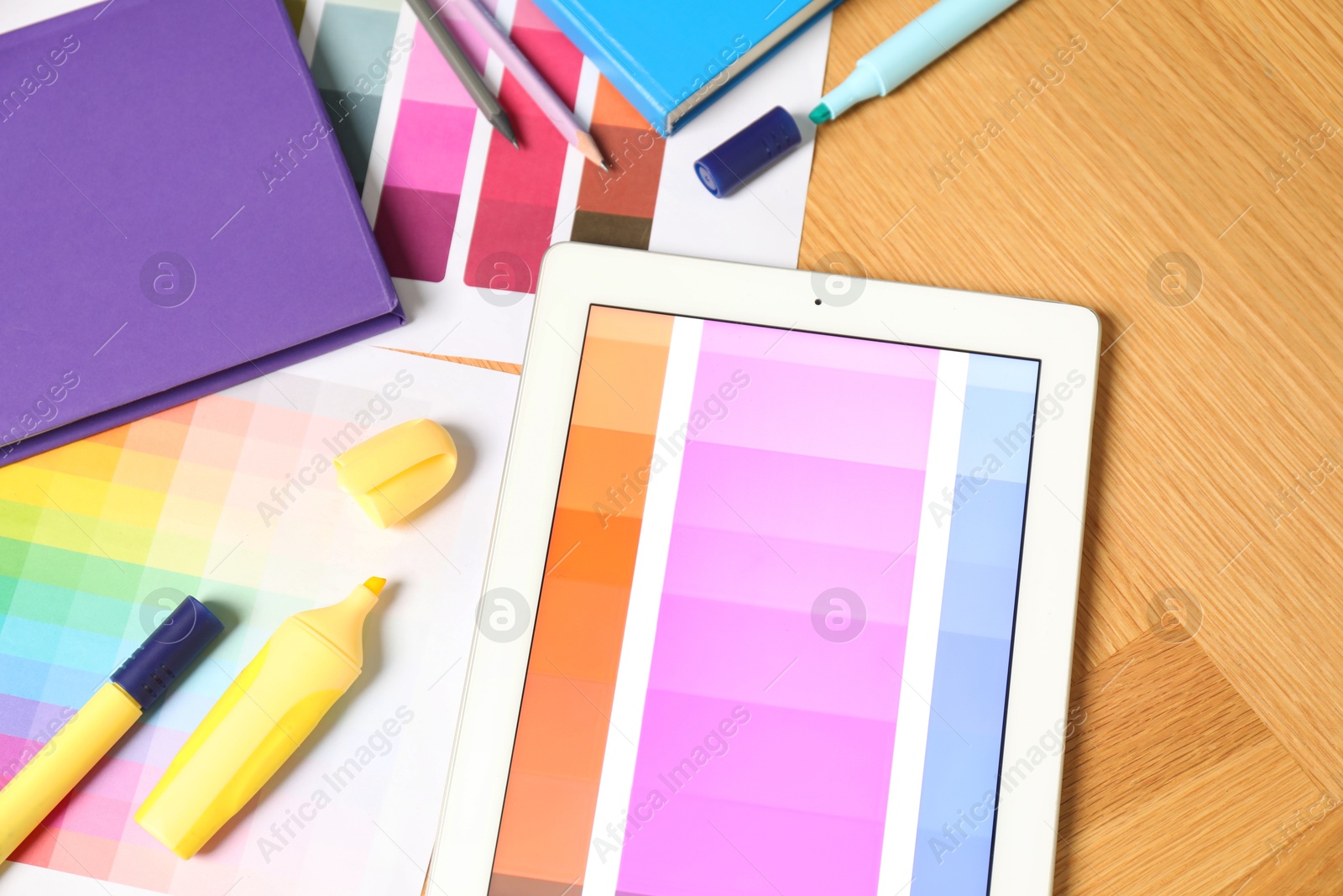 Photo of Designer's workplace with tablet, palettes and stationery on wooden table, top view