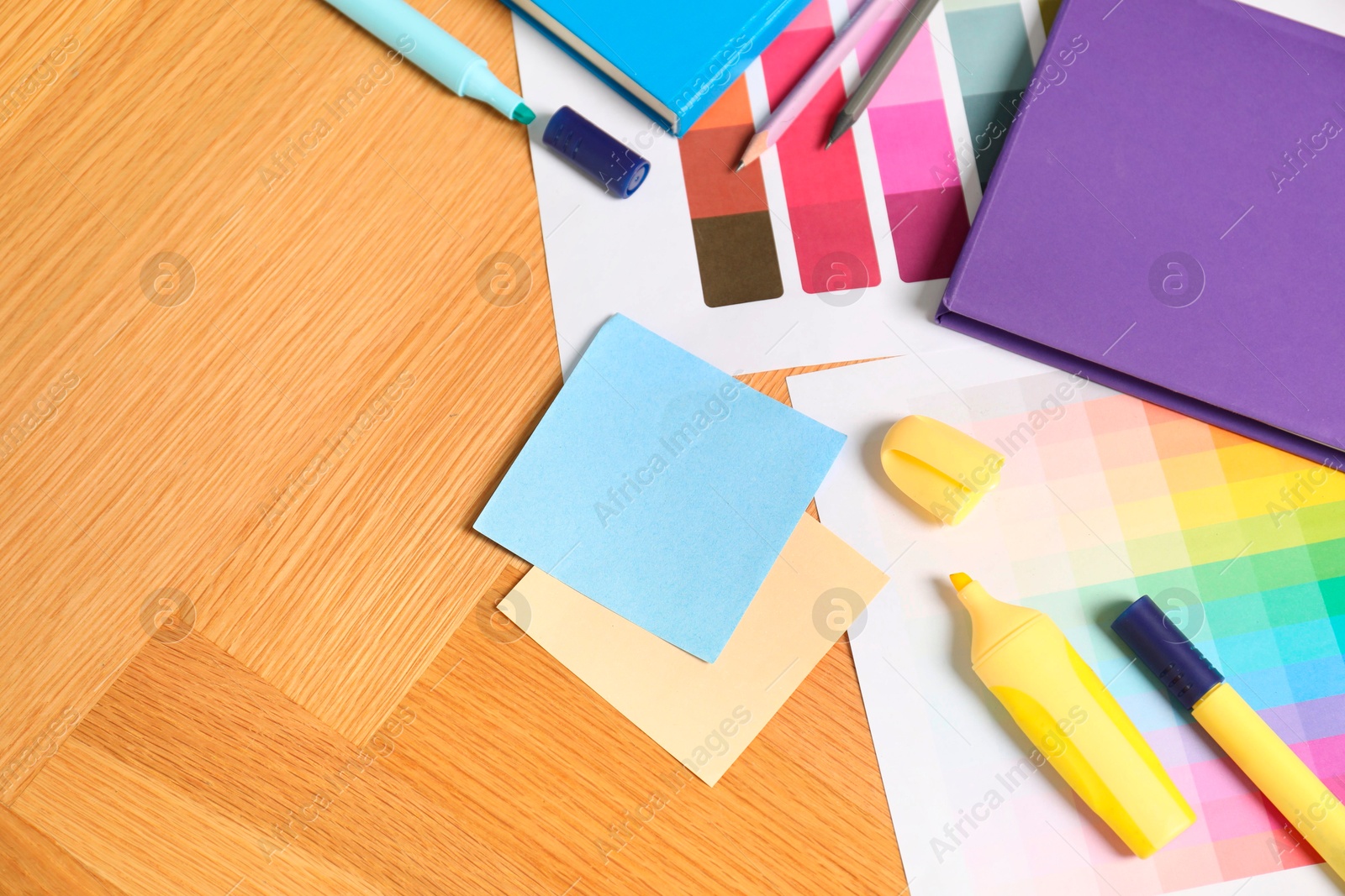 Photo of Designer's workplace with different color palettes and stationery on wooden table, top view