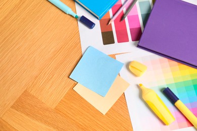 Photo of Designer's workplace with different color palettes and stationery on wooden table, top view