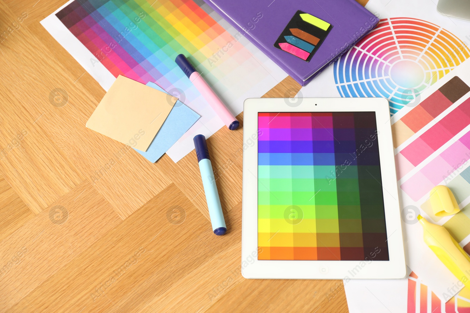 Photo of Designer's workplace with tablet, palettes and stationery on wooden table, above view