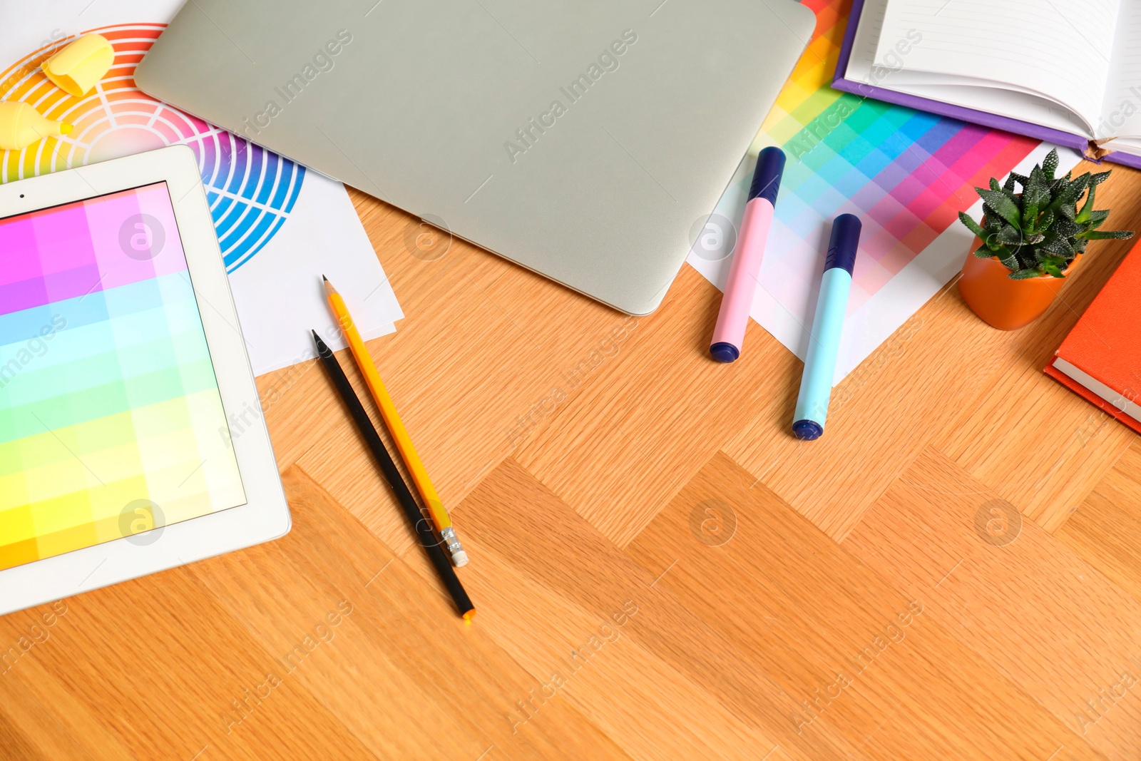 Photo of Designer's workplace with laptop, tablet, palettes and stationery on wooden table, above view