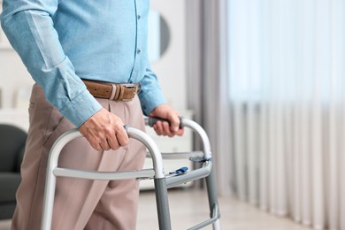 Photo of Senior man using walking frame at home, closeup. Space for text