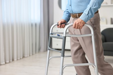 Photo of Senior man using walking frame at home, closeup. Space for text