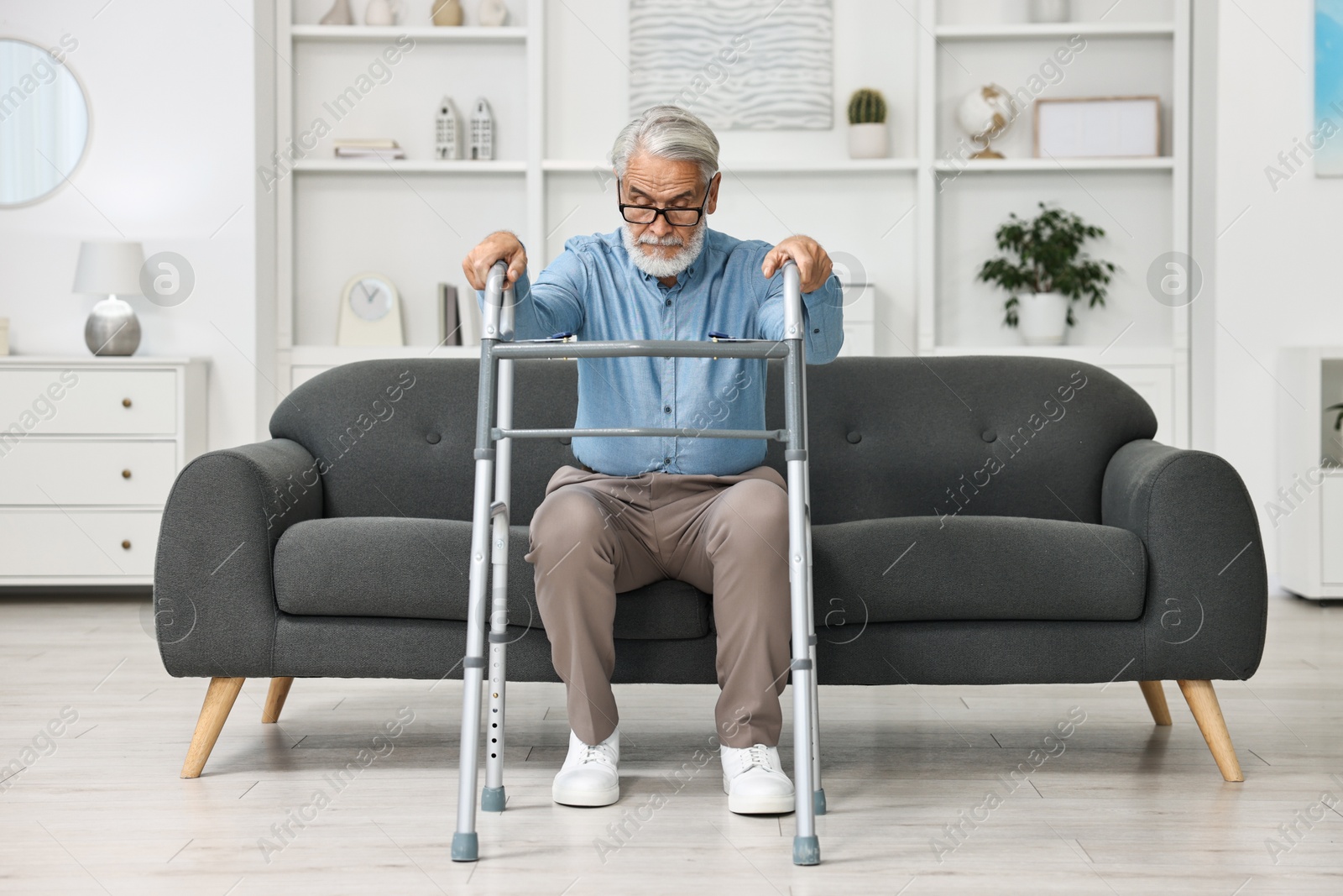 Photo of Senior man with walking frame on sofa at home